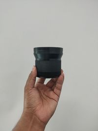 Close-up of hand holding guitar against white background
