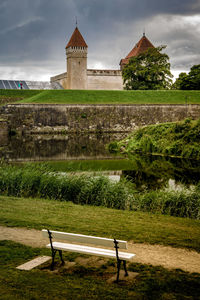 Park bench by building against sky