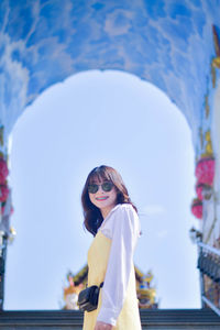 Portrait of young woman standing against sky