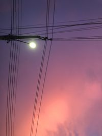 Low angle view of electricity pylon against sky during sunset