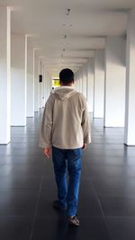 Rear view of man walking in corridor of building