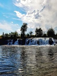 Scenic view of waterfall against sky