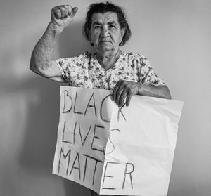 Portrait of woman holding paper with text against wall