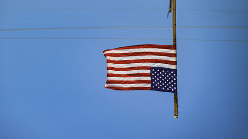 Low angle view of flag against clear blue sky