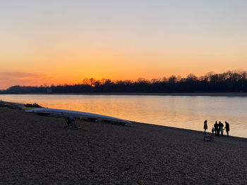 People on beach against sky during sunset