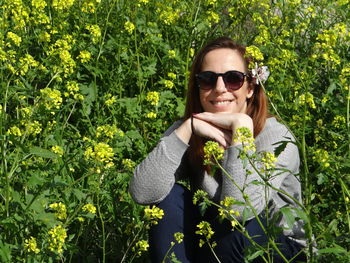 Portrait of young woman wearing sunglasses while sitting amidst plants