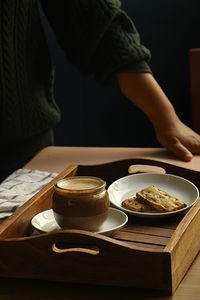 Midsection of woman holding coffee cup on table