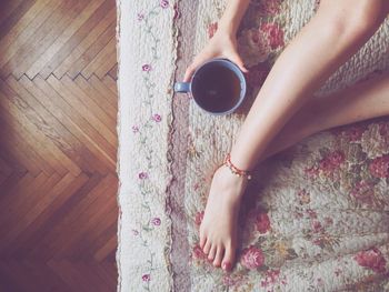 High angle view of woman with black tea sitting on rug at home