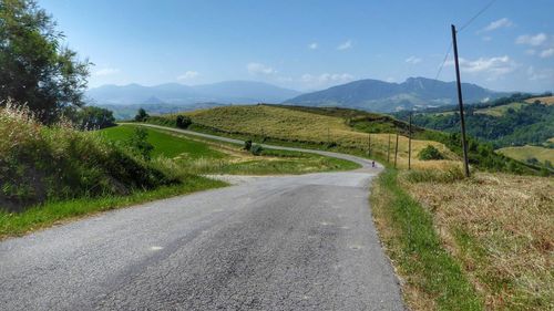 Road amidst green landscape against sky