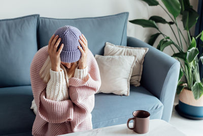 Midsection of woman sitting on bed at home