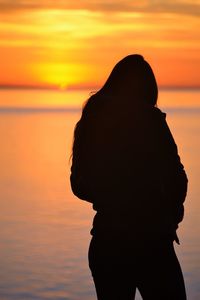 Silhouette of person in front of sea during sunset