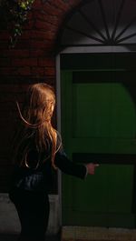 Rear view of girl pointing at closed door