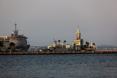 View of buildings by sea against sky in city