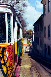 Painted tram on railroad tracks in city by buildings