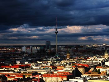 Fernsehturm amidst building against cloudy sky at dusk