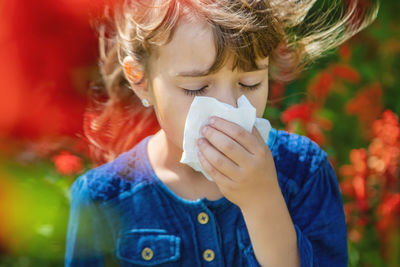 Close-up of girl wiping nose with tissue