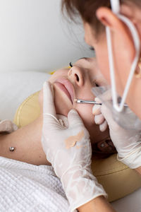 High angle view of young woman drinking milk while lying on bed at home