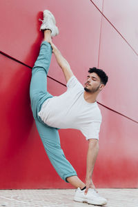 Male dancer practicing arabesque position while leaning on wall