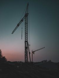 Low angle view of crane at construction site against sky