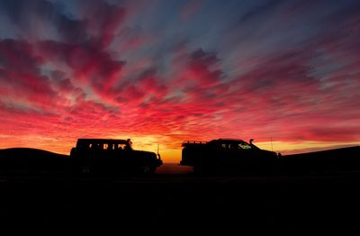 Silhouette built structure against orange sky