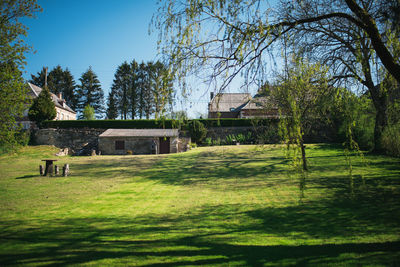 House on field by trees against sky