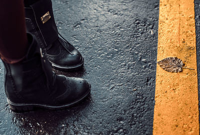 Low section of person standing on wet road