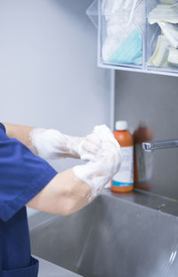 Midsection of person washing hands in sink