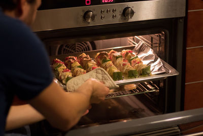 Midsection of man preparing food in oven at home