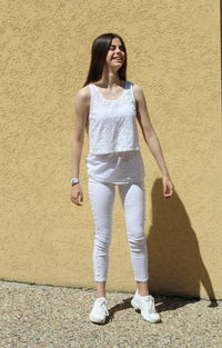 Portrait of smiling young woman standing against wall