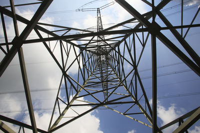 Low angle view of electricity pylon against blue sky