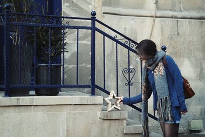 Woman touching star shape decoration on steps by blue railing