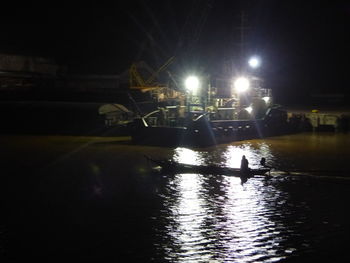 People on illuminated street by river at night