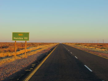 Information sign by road on landscape against clear sky