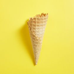 Close-up of ice cream cone against yellow background