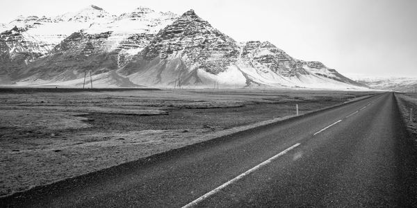 Road by snowcapped mountain against sky