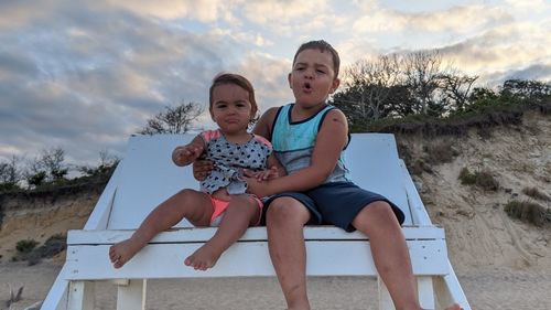 Happy friends sitting against sky