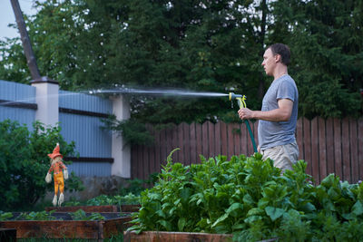 Jet spraying of water in daylight. a man is watering outdoor plants in the garden