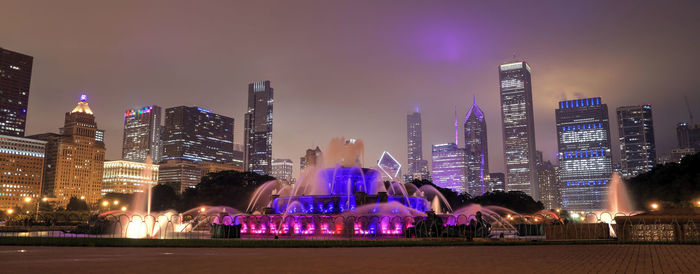 Illuminated buildings in city against sky at night