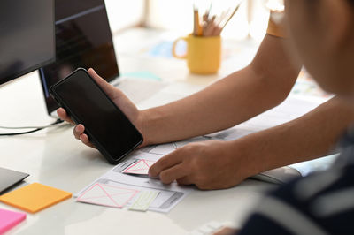 Midsection of man using mobile phone on table