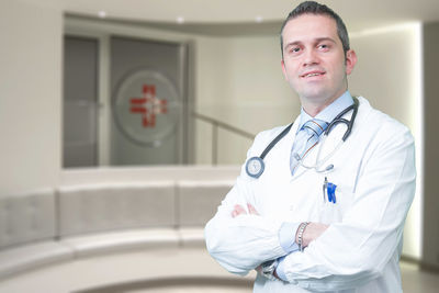 Portrait of confident male doctor with arms crossed standing in hospital