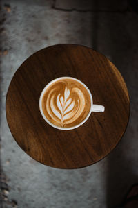 Latte art coffee on wooden table in coffee shop