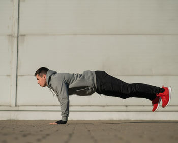 Side view of young woman exercising on floor