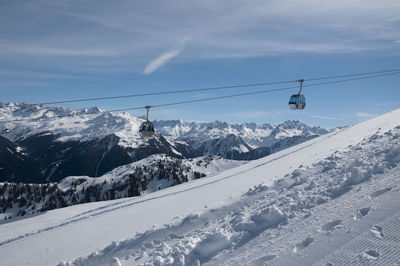 Overhead cable cars hanging over snowcapped mountains against sky