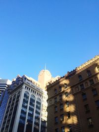 Low angle view of buildings against clear blue sky