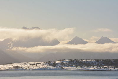 Scenic view of snowcapped mountains by sea against sky