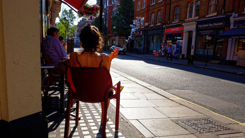 Rear view of people sitting on street in city