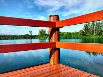 Red pier on lake against sky