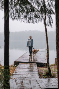 Attractive caucasian woman with brown nova scotia duck tolling retriever walking on a wooden pier