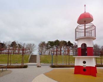 Red tower by footpath against sky