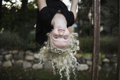 Portrait of playful girl hanging on monkey bars at playground